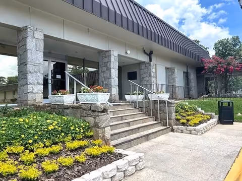 Exterior view of Sadie G. Mays Health & Rehabilitation Center entrance with stairs, stone columns, planters.