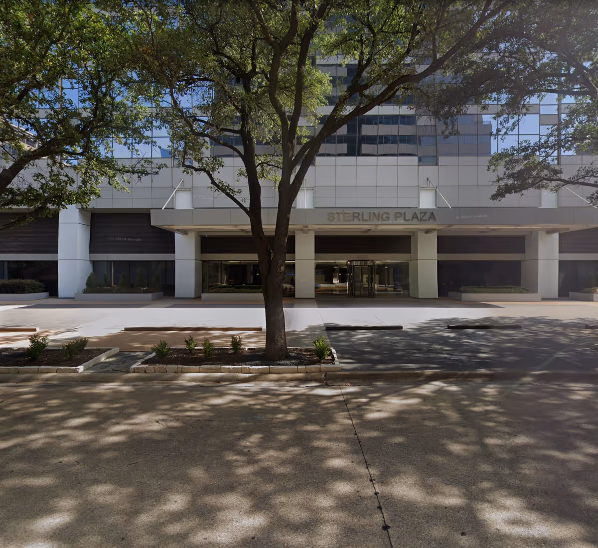 Front view of a modern building entrance with a tree in the foreground.