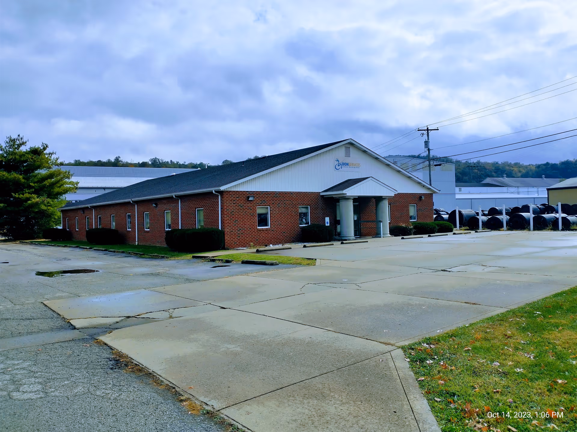 Exterior view of a single-story brick building with a parking lot and cloudy sky.