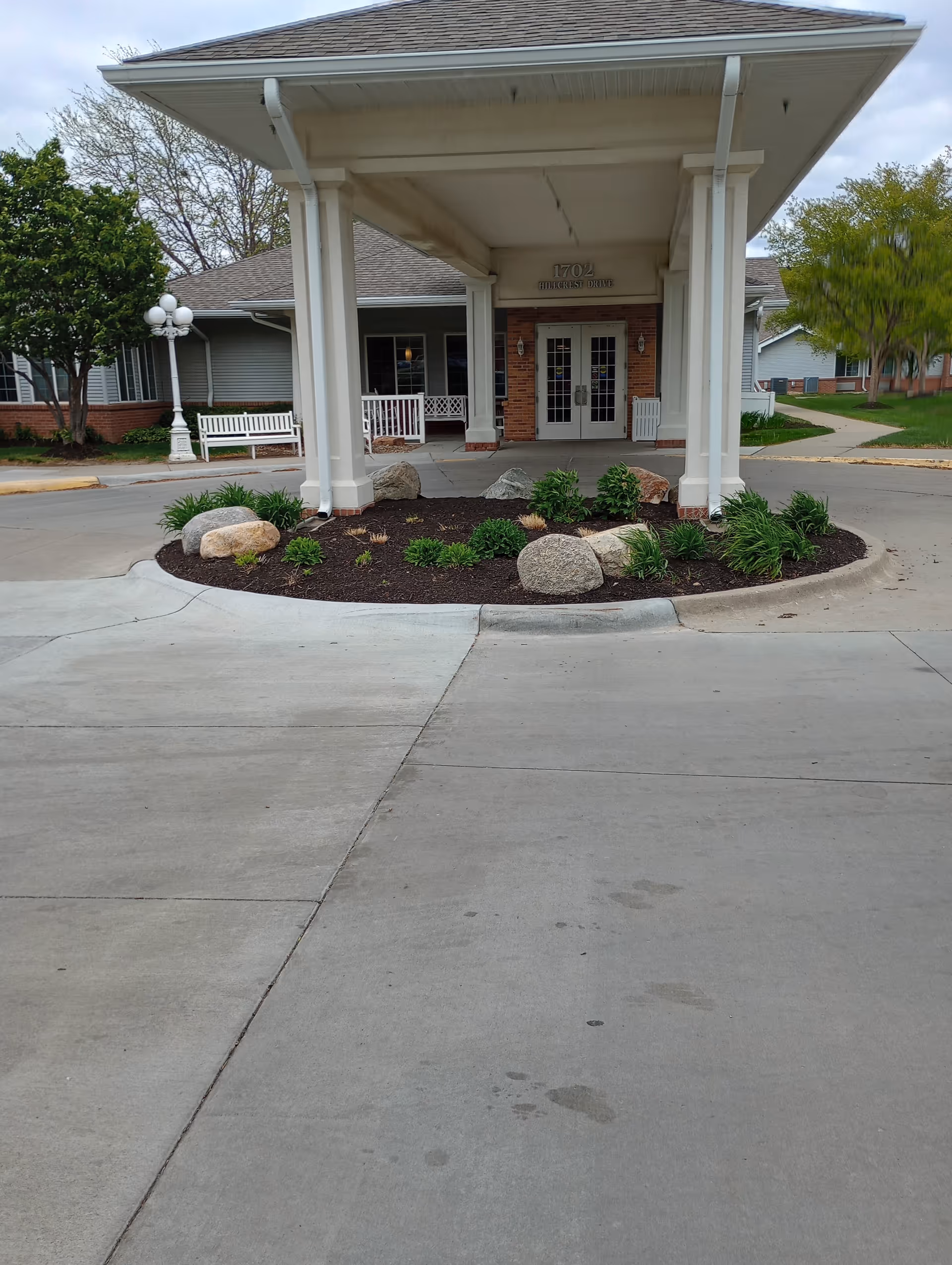 Exterior view of facility entrance with a covered drop-off and landscaped garden.