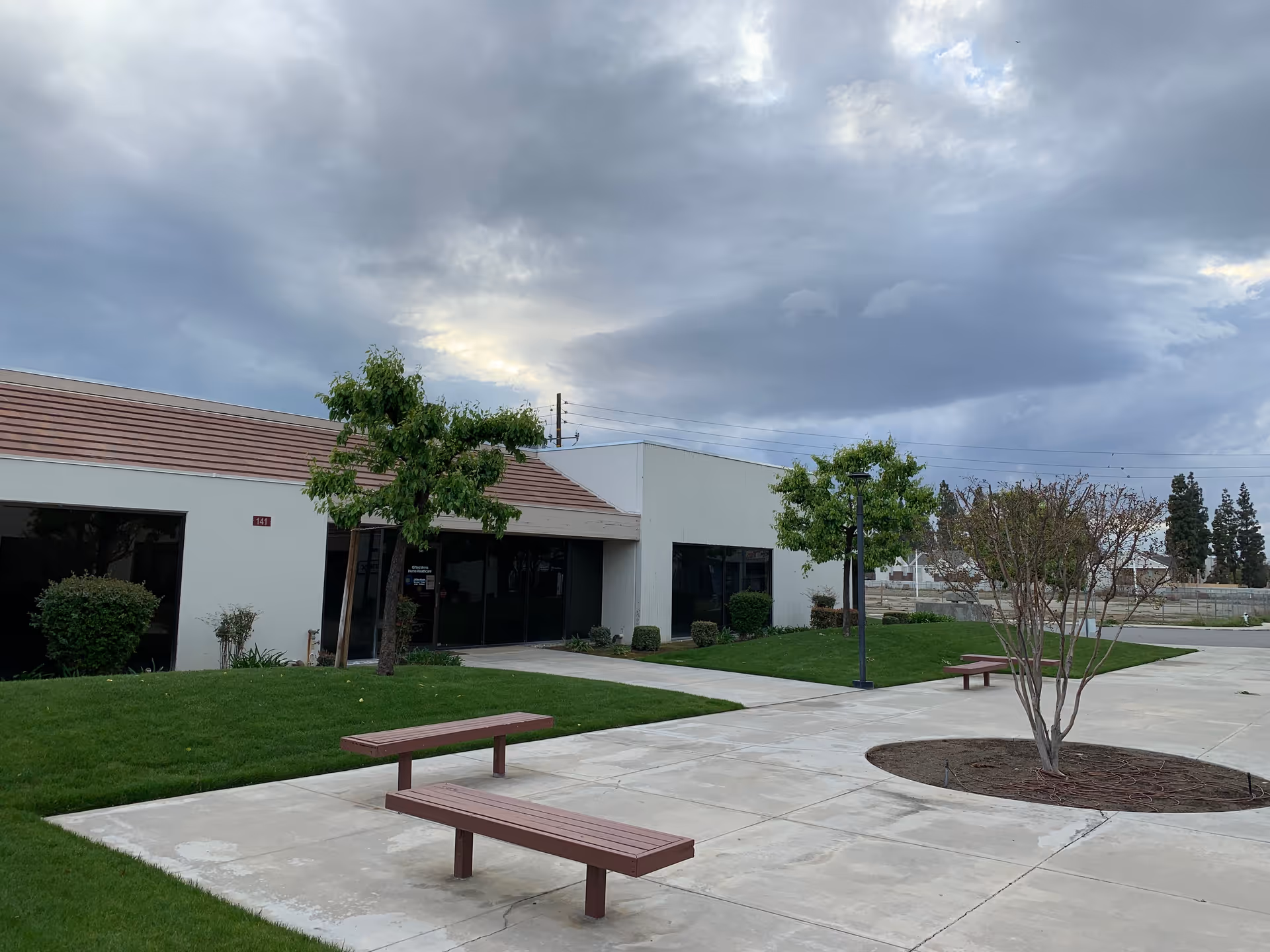Exterior view of Gifted Arms Home Healthcare Services with benches and landscaped courtyard.