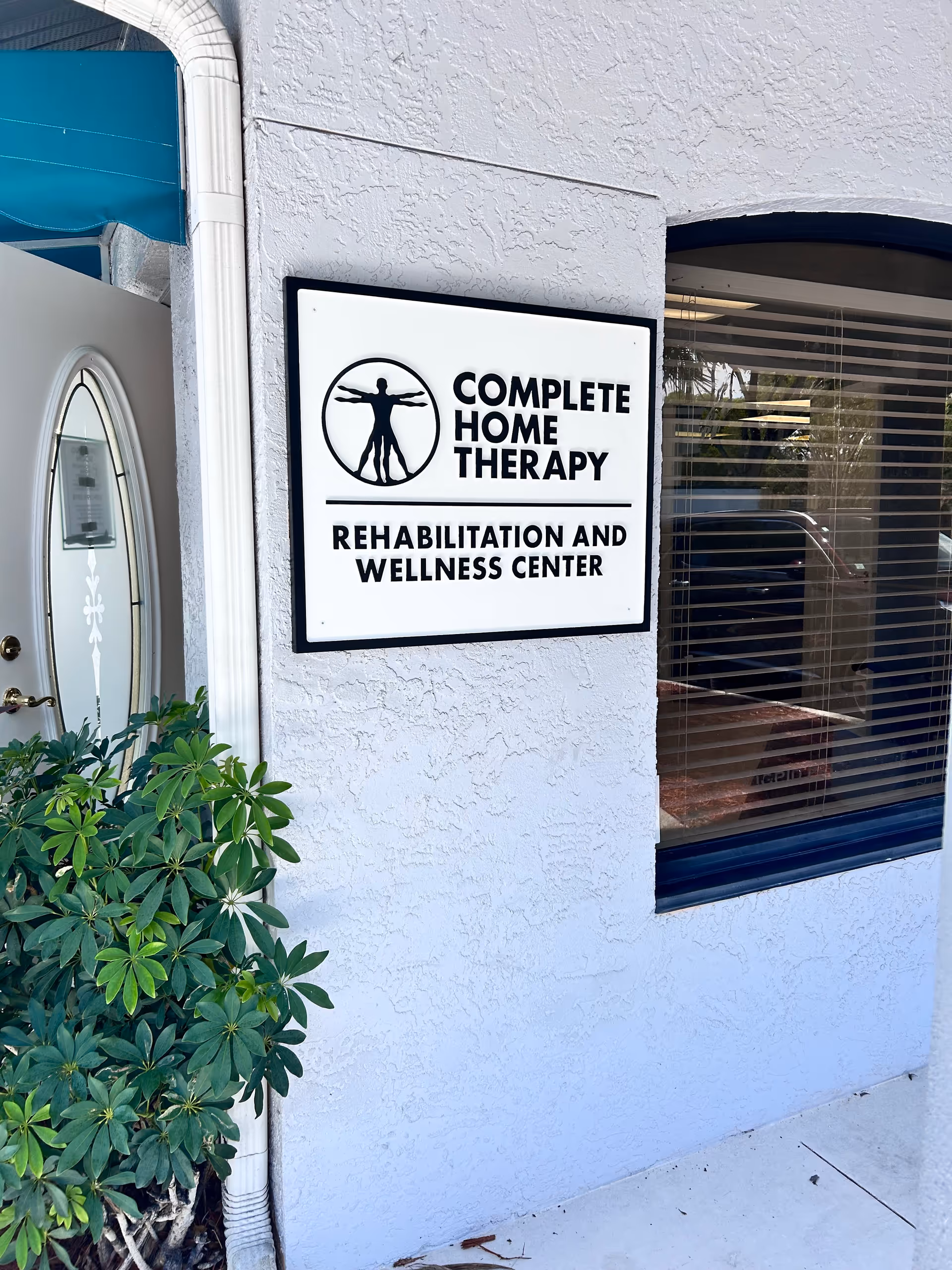 Outside wall with Complete Home Therapy sign beside a window and doorway.