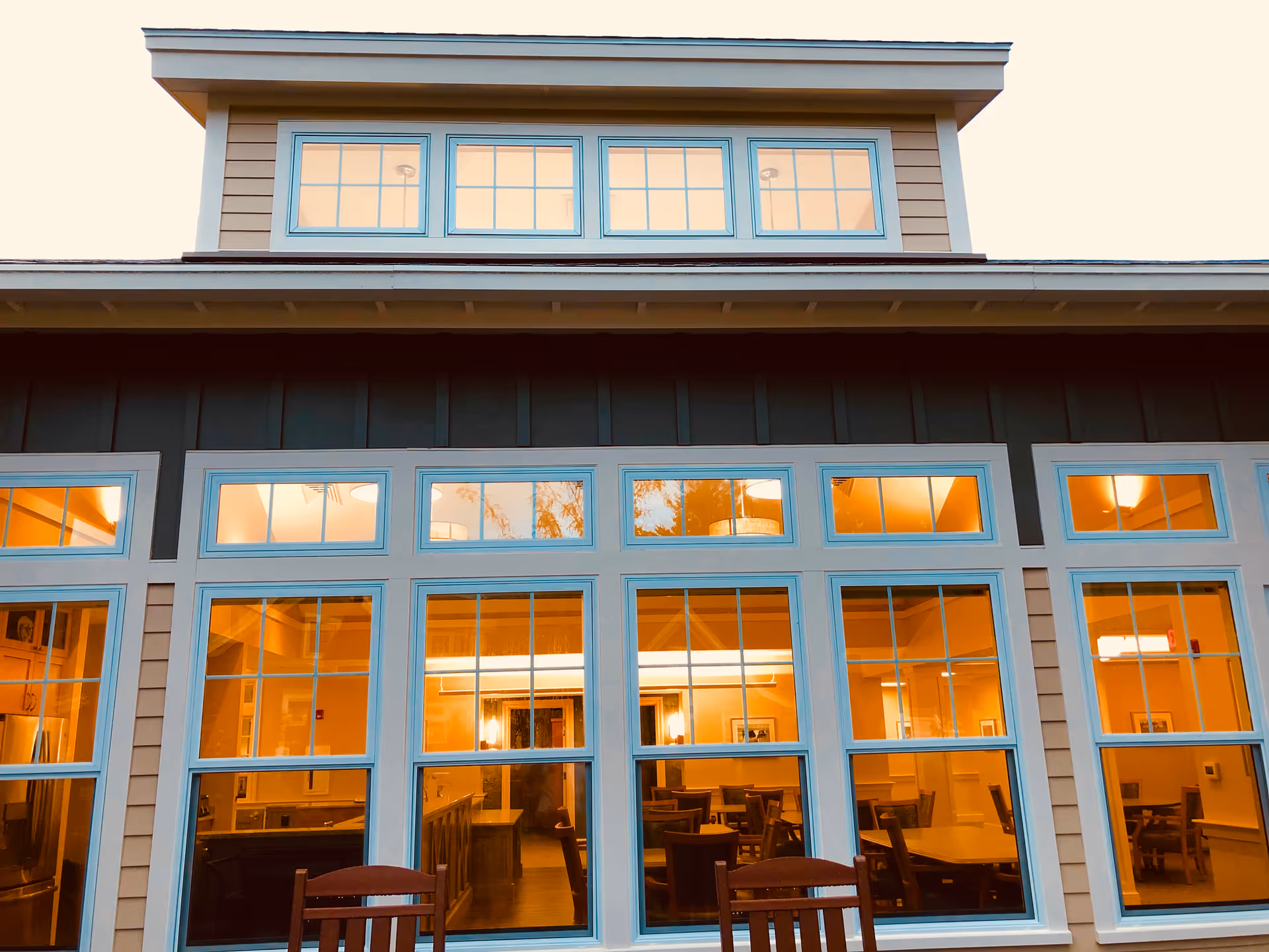 Modern senior living facility exterior with large windows glowing orange from interior lighting.