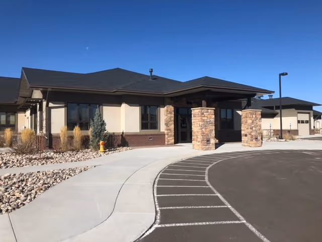 Exterior view of Hospice of Laramie facility entrance with stone pillars.