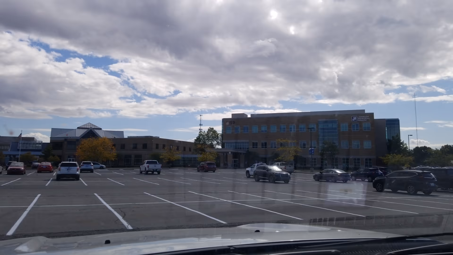 Parking lot in foreground with a brick medical facility and a cloudy sky.