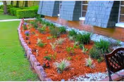 Exterior view of a nursing home with a landscaped garden bed and bench.