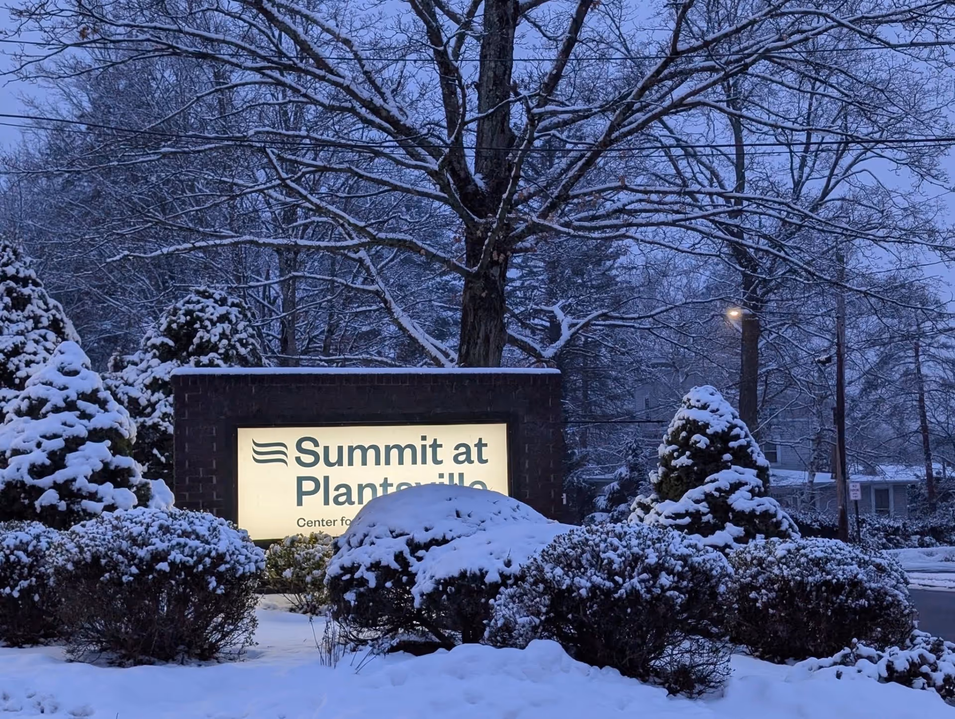 Snow-covered landscaping surrounds the Summit at Plantsville exterior sign.
