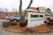 Exterior view of Elizabeth Wright Apartments sign with parking and landscaping.