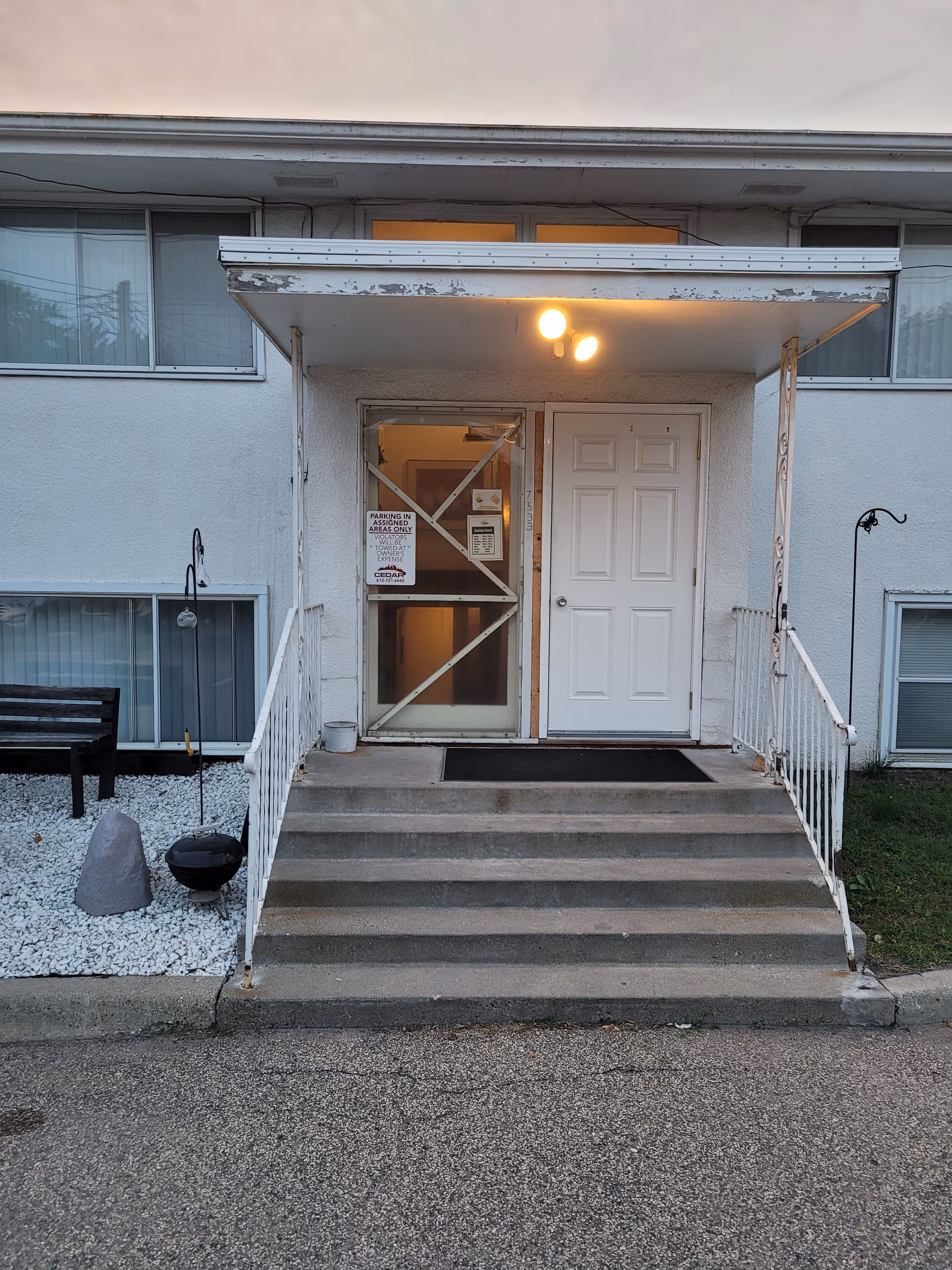 Front entrance of a senior care facility with stairs and a lit doorway.