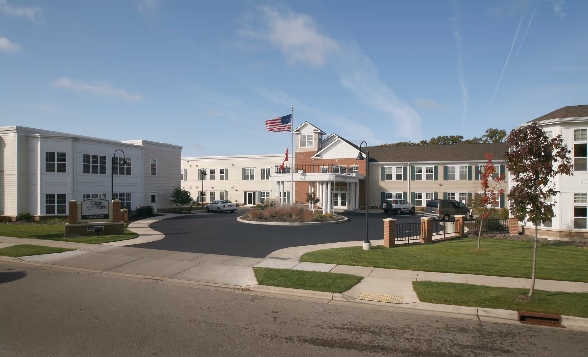 Exterior view of Oak Park Place Autumn Lane II, senior living facility, with entrance and flags.