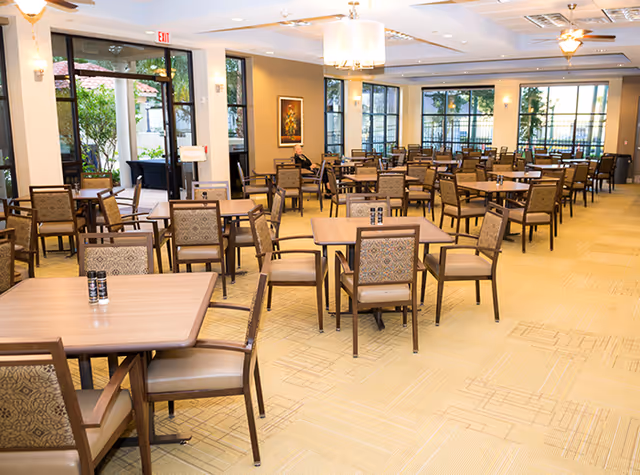 Dining hall at Carla's Caring Hands Senior Living with multiple tables and chairs.