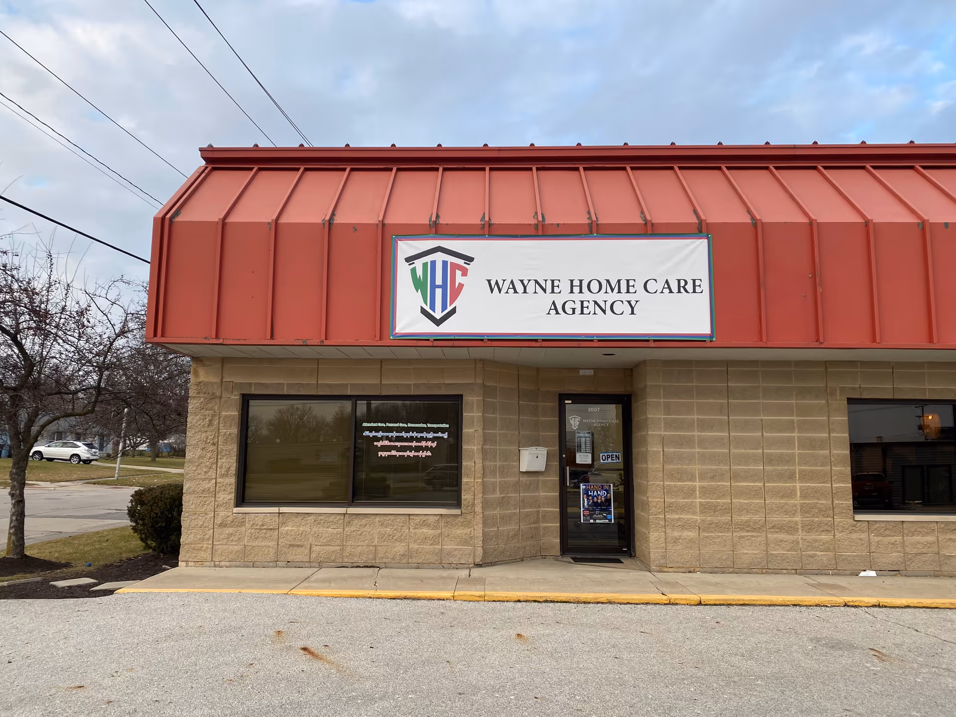 Exterior of a brick building with a red metal awning and Wayne Home Care Agency sign.