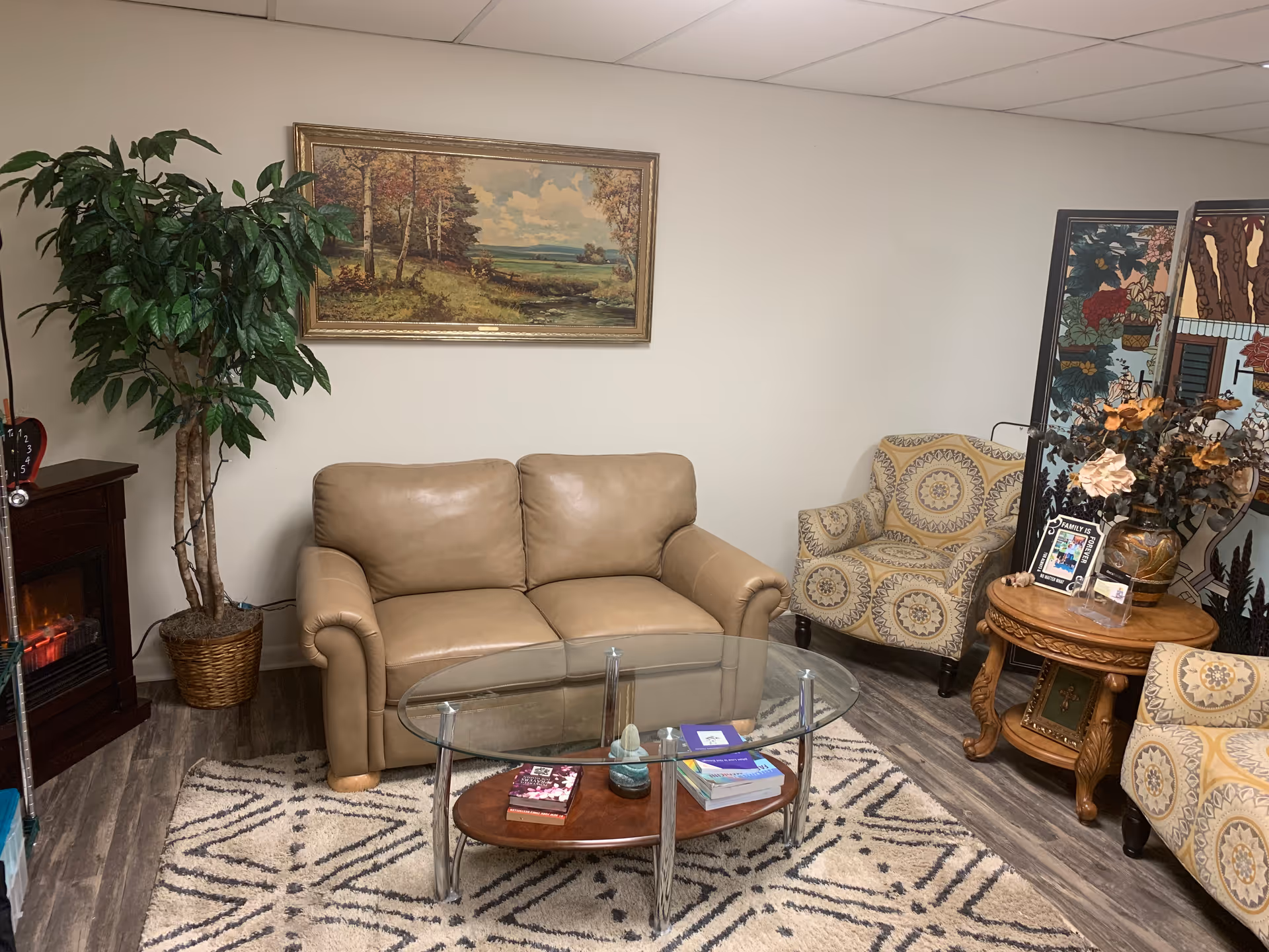 Cozy living room area with beige sofa, glass coffee table, plants, and decorative screen.