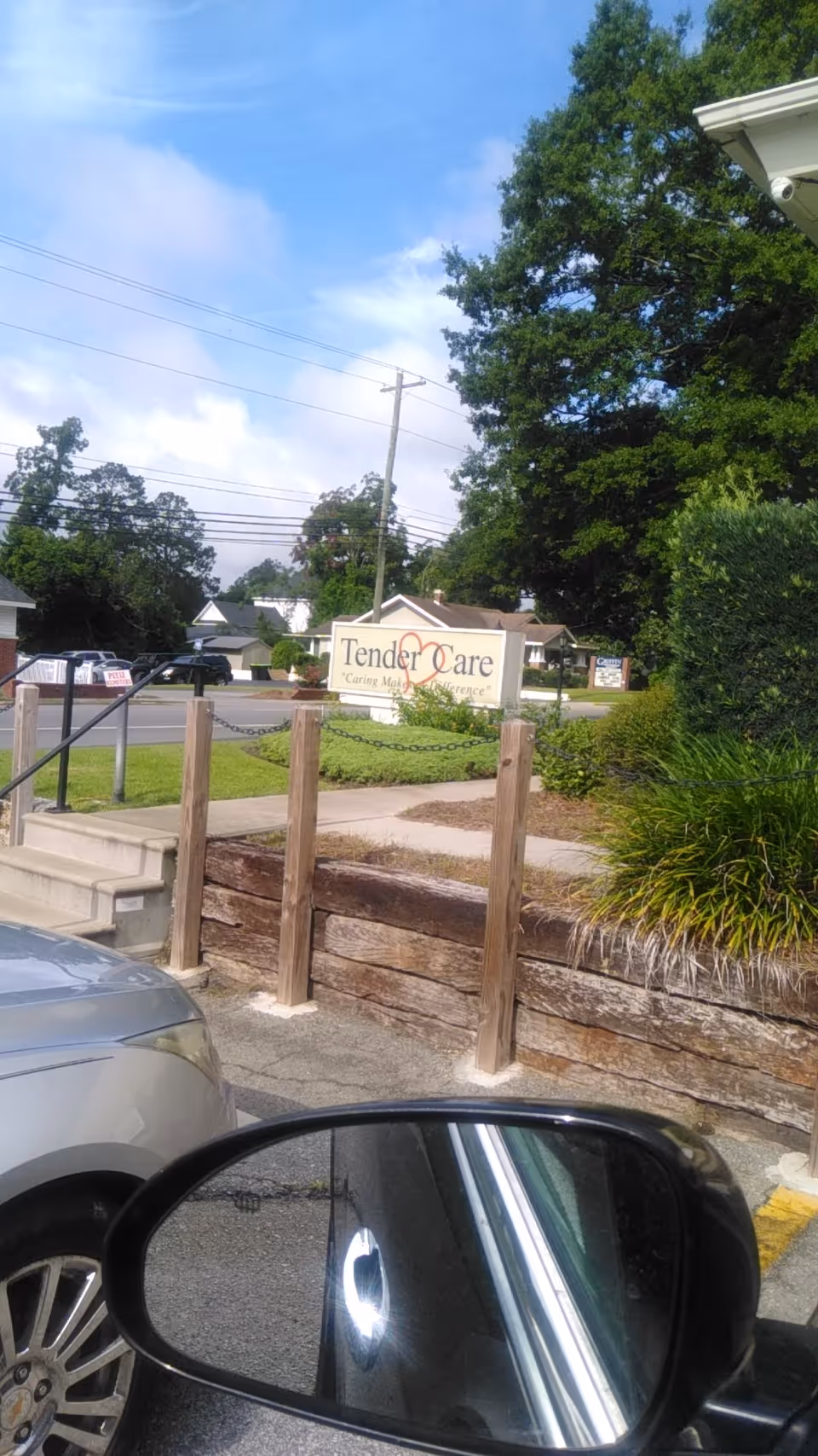 Outdoor view of Tender Care facility sign with entrance and parking area.