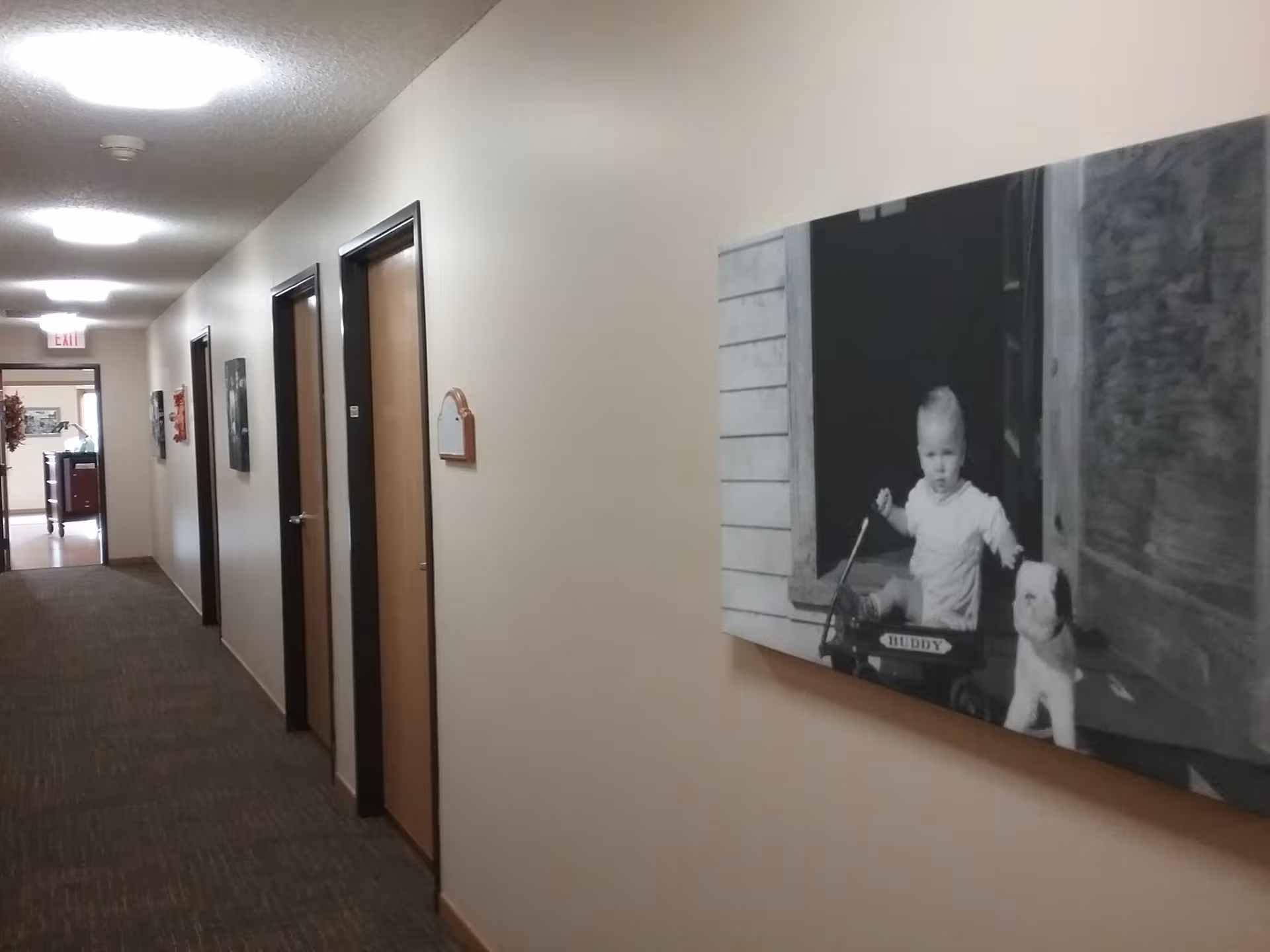 Interior corridor at Edgewood Mitchell Memory Care with closed doors and wall art.