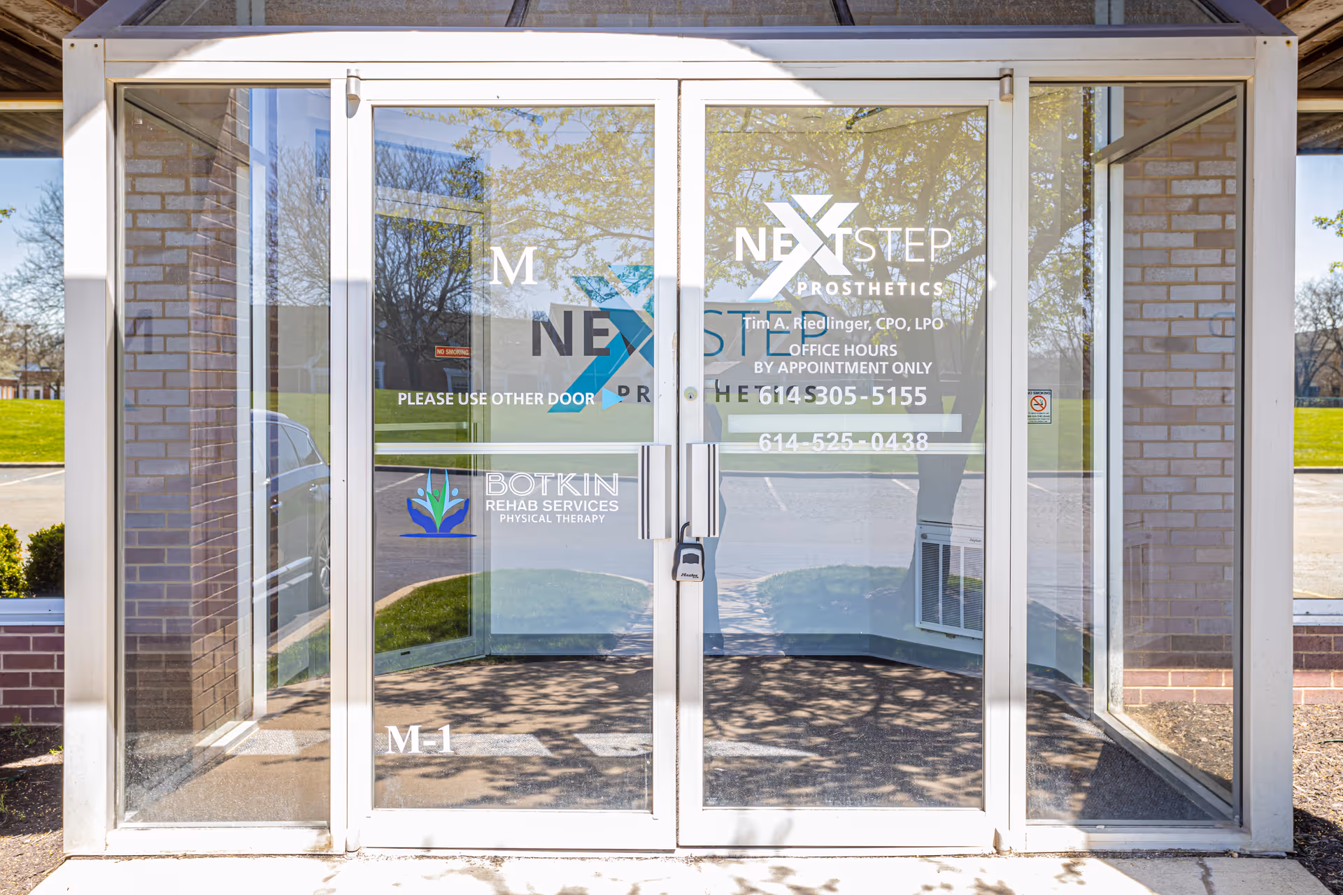 Glass entrance doors displaying Botkin Rehab Services and Next Step Prosthetics signage.