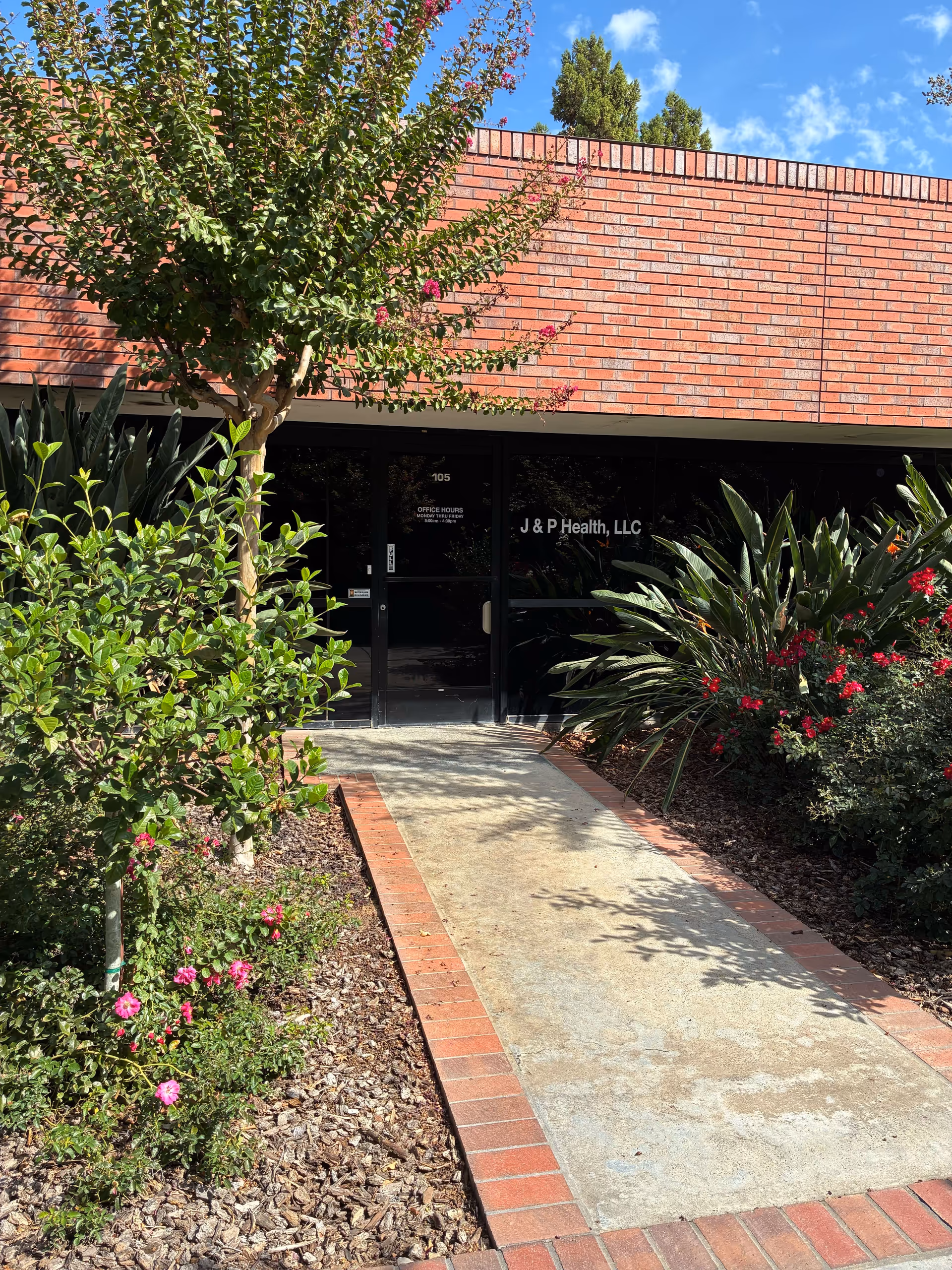 Front entrance of J & P Health, LLC with brick exterior and landscaped walkway.