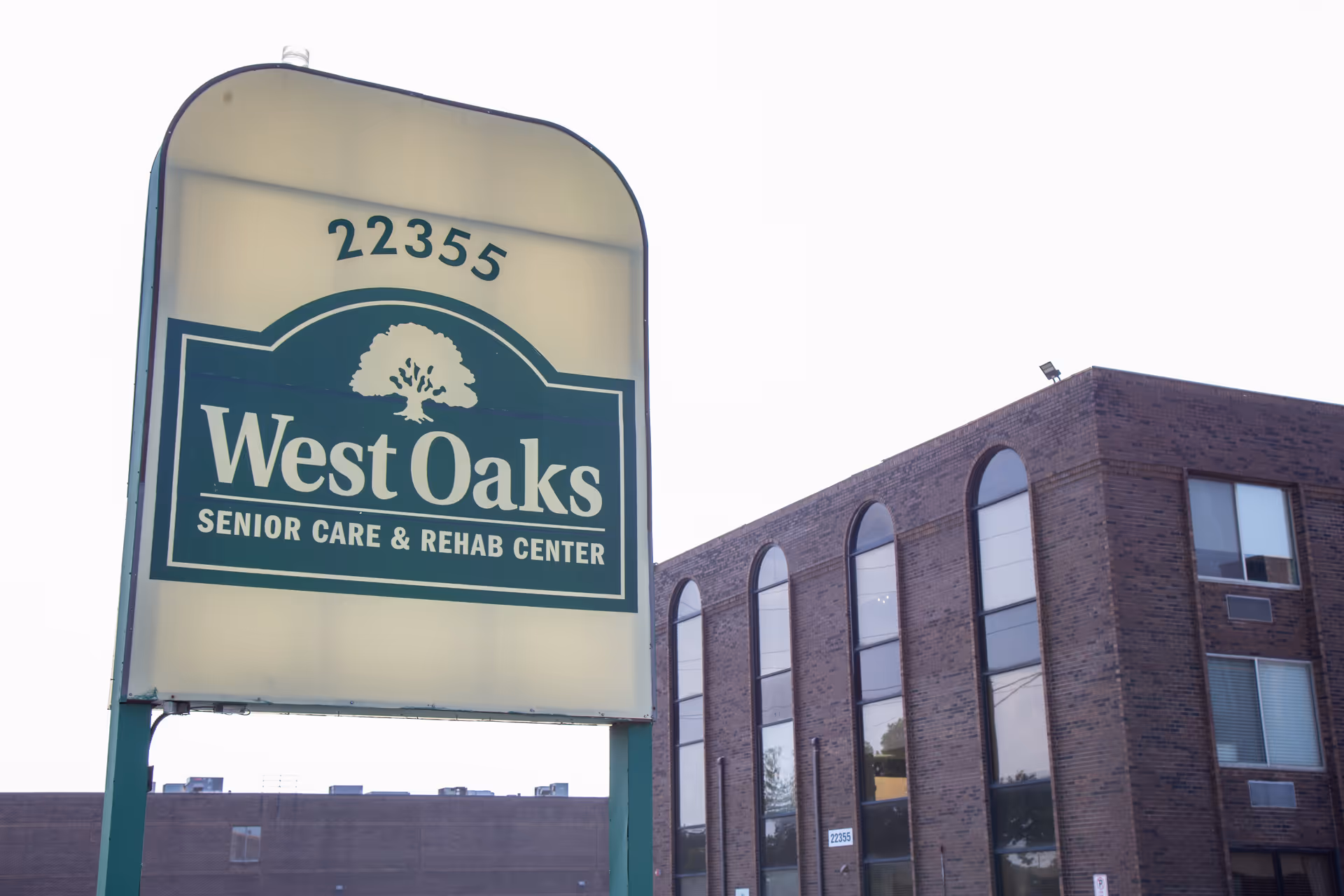 A large West Oaks sign beside a brick senior care and rehab center exterior.