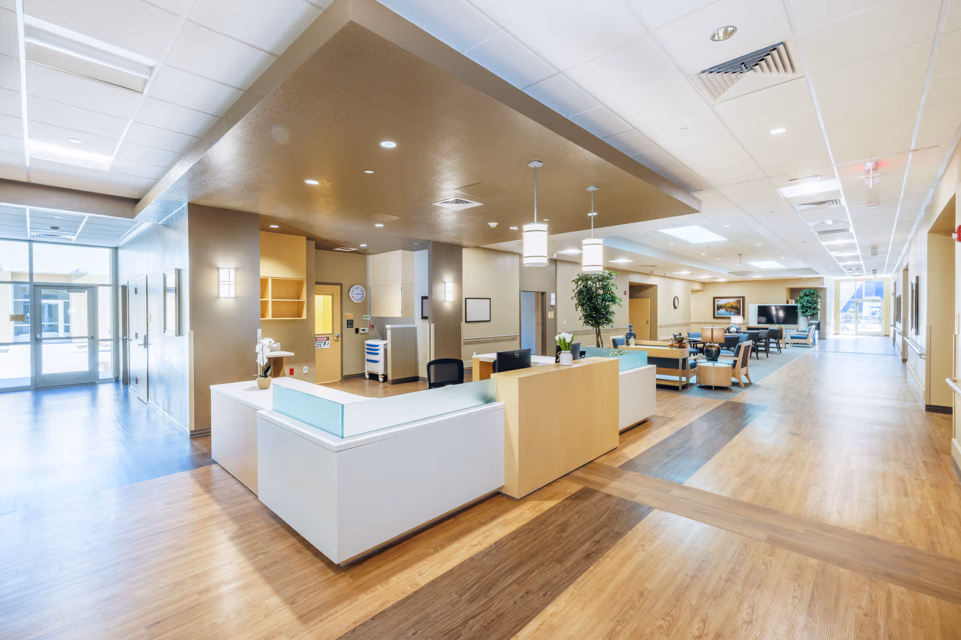 Modern senior living lobby with reception desk, seating, and wide hallways.