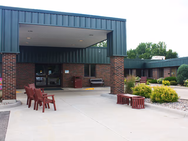 Exterior view of Good Samaritan Society - Mountain Lake entrance with brick columns and seating.