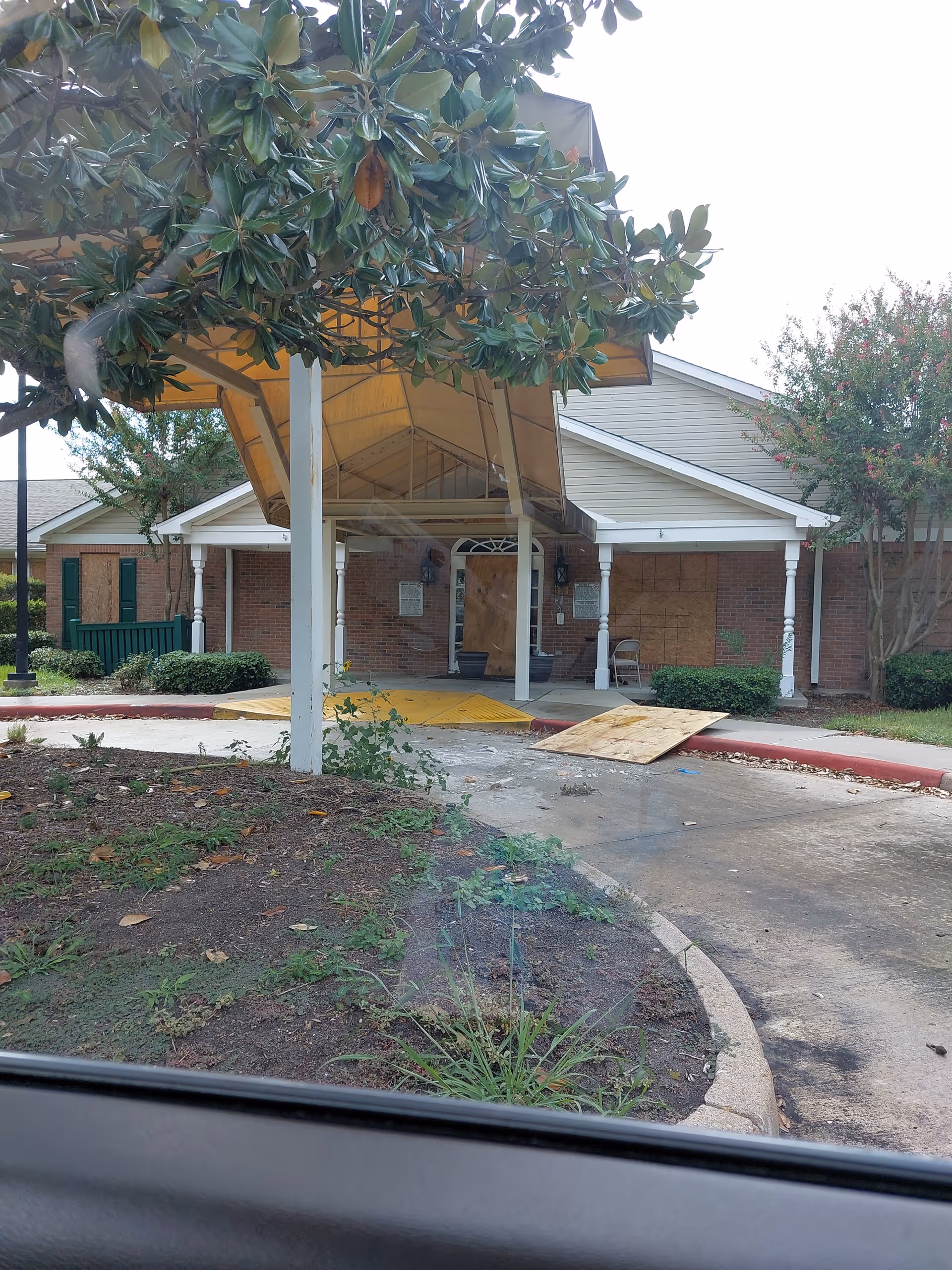 Exterior view of the facility entrance with a canopy and scattered wooden boards.