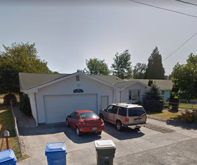 Front view of a single-story house with a double garage and two parked cars.