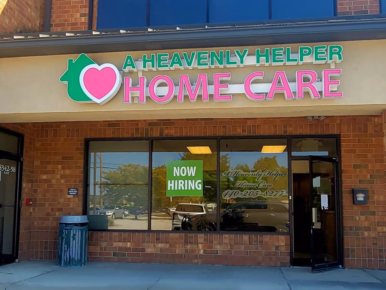 Exterior storefront of A Heavenly Helper Home Care with a Now Hiring sign in the window.