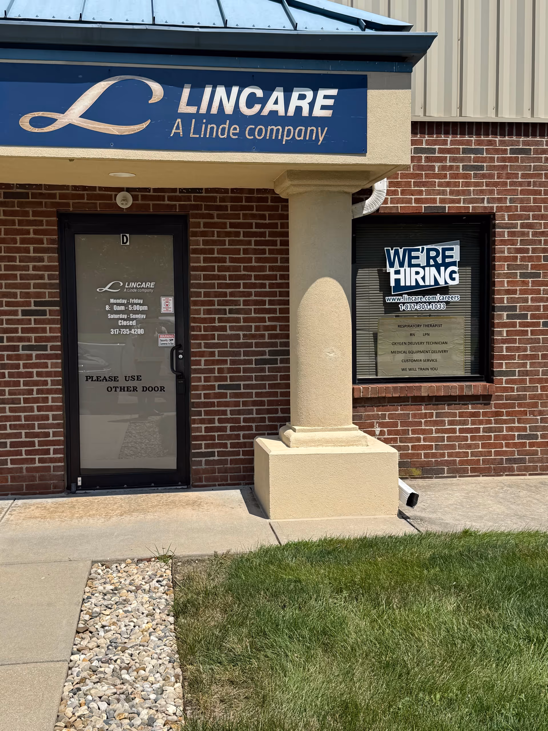 Brick exterior of a LinCare facility with a blue sign and hiring window.