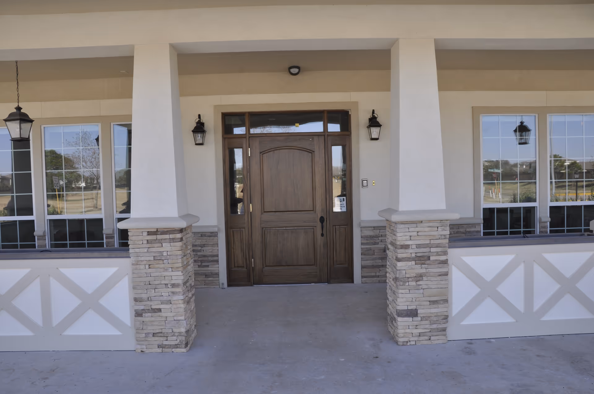 Entrance of a senior living facility with a wooden door, stone columns, and large windows.