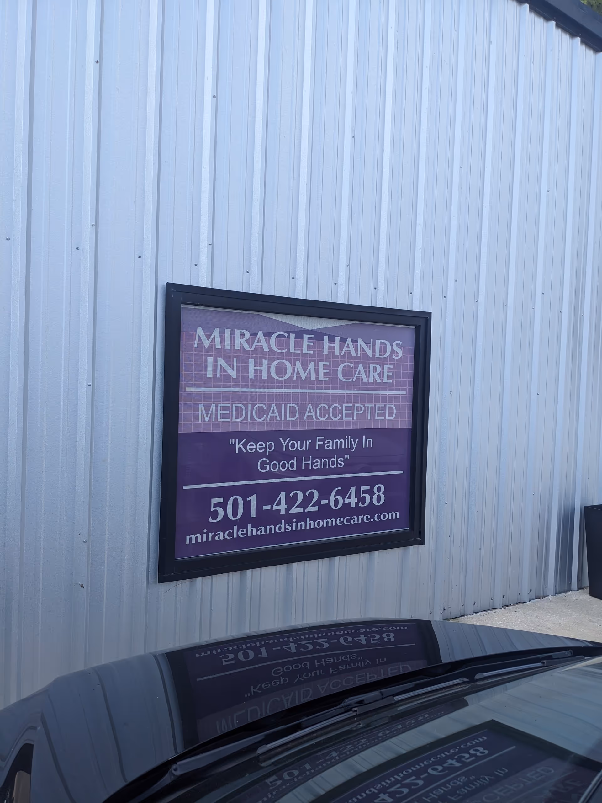 Exterior metal wall with a purple Miracle Hands In Home Care sign.