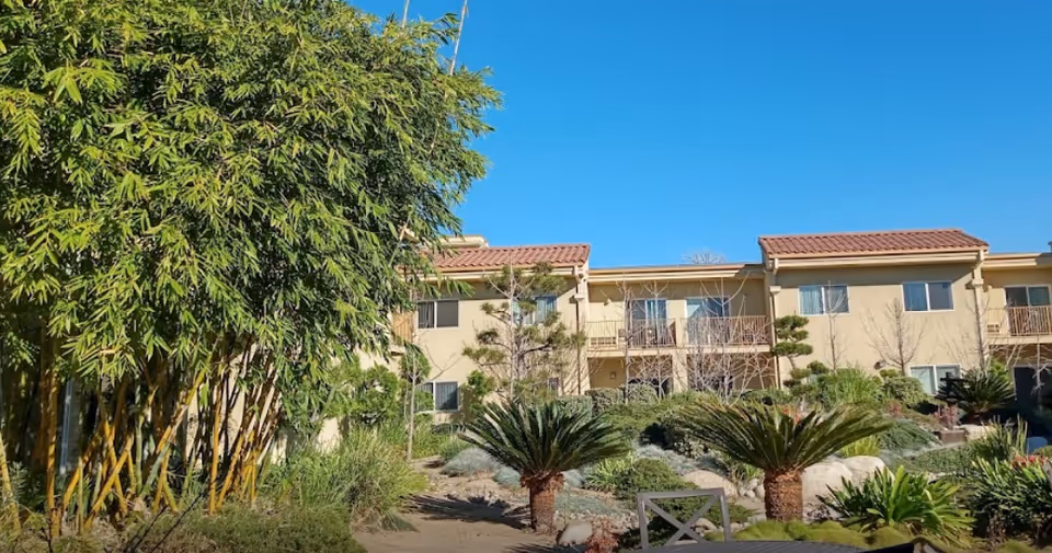 Exterior view of Nikkei Senior Gardens building with palm trees and landscaped shrubbery