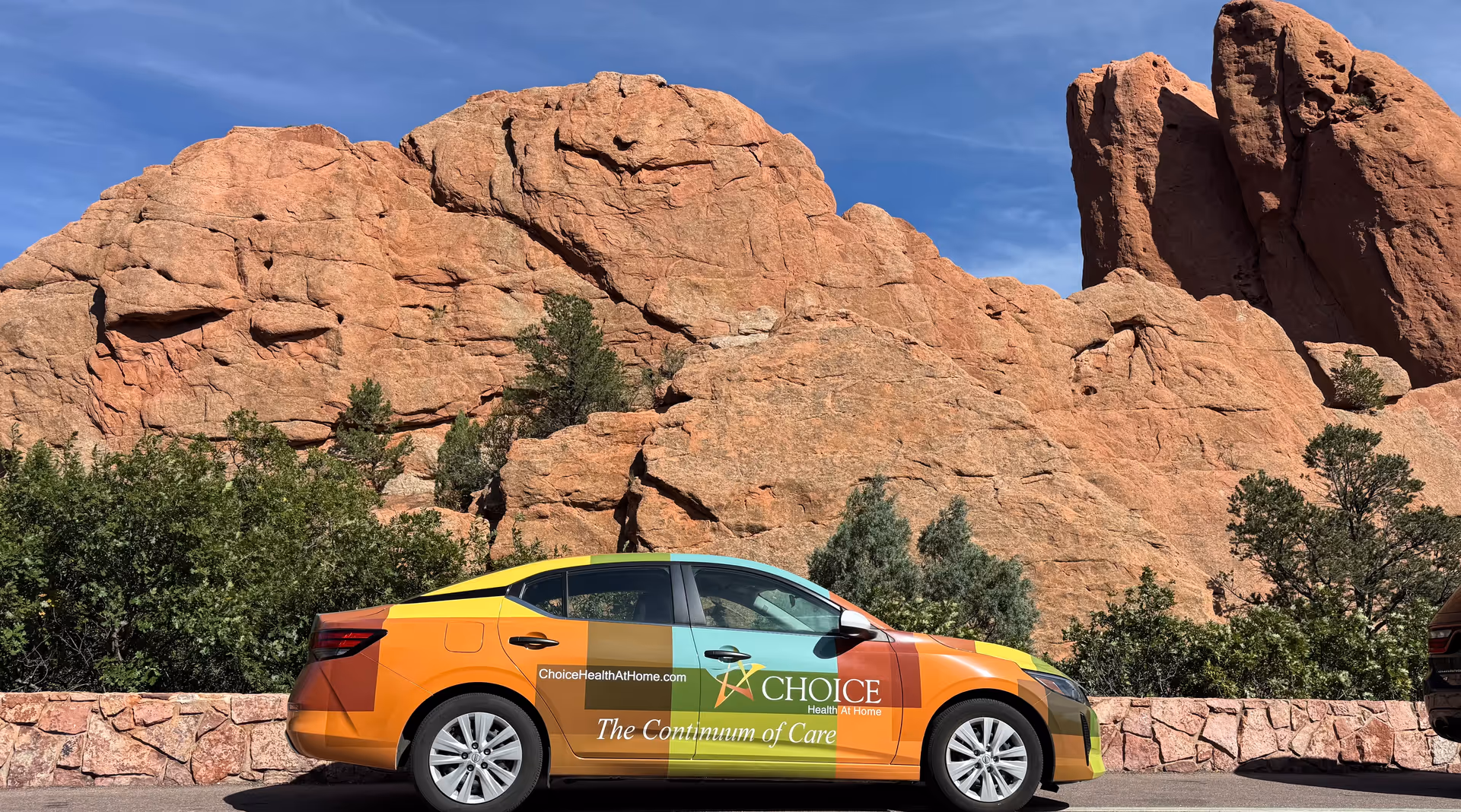 Branded Choice Hospice promotional car parked outdoors beside red rock formations.