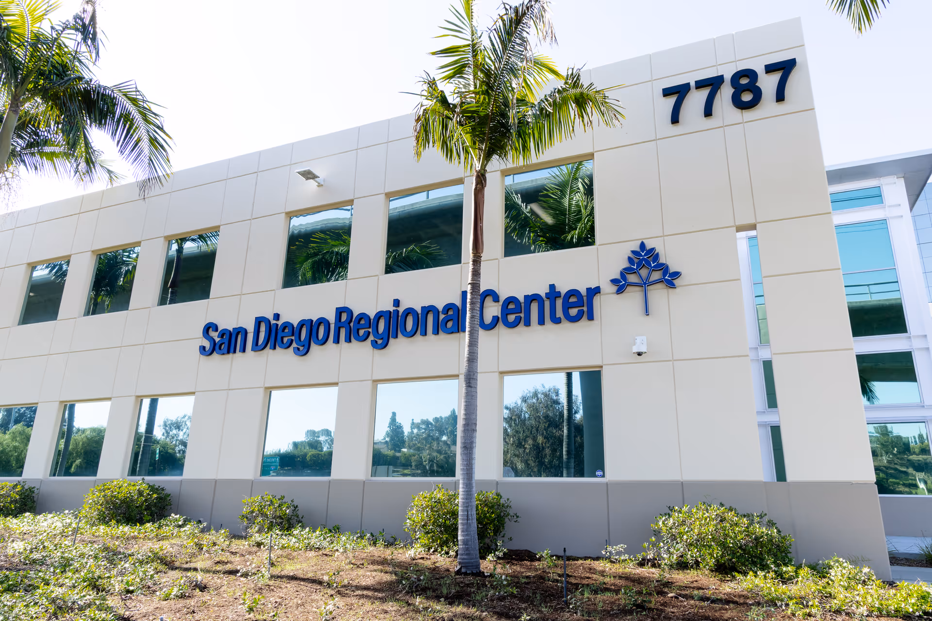 Modern facility building with palm trees and San Diego Regional Center signage.