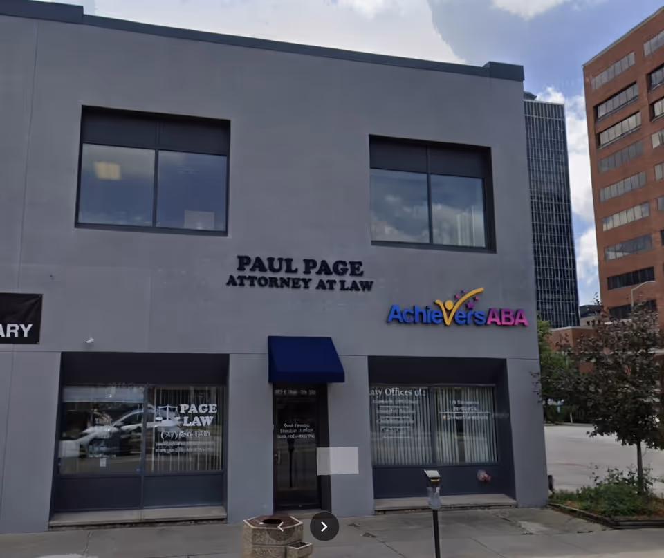 Gray commercial building front with two large windows and Achievers ABA sign beside attorney offices.