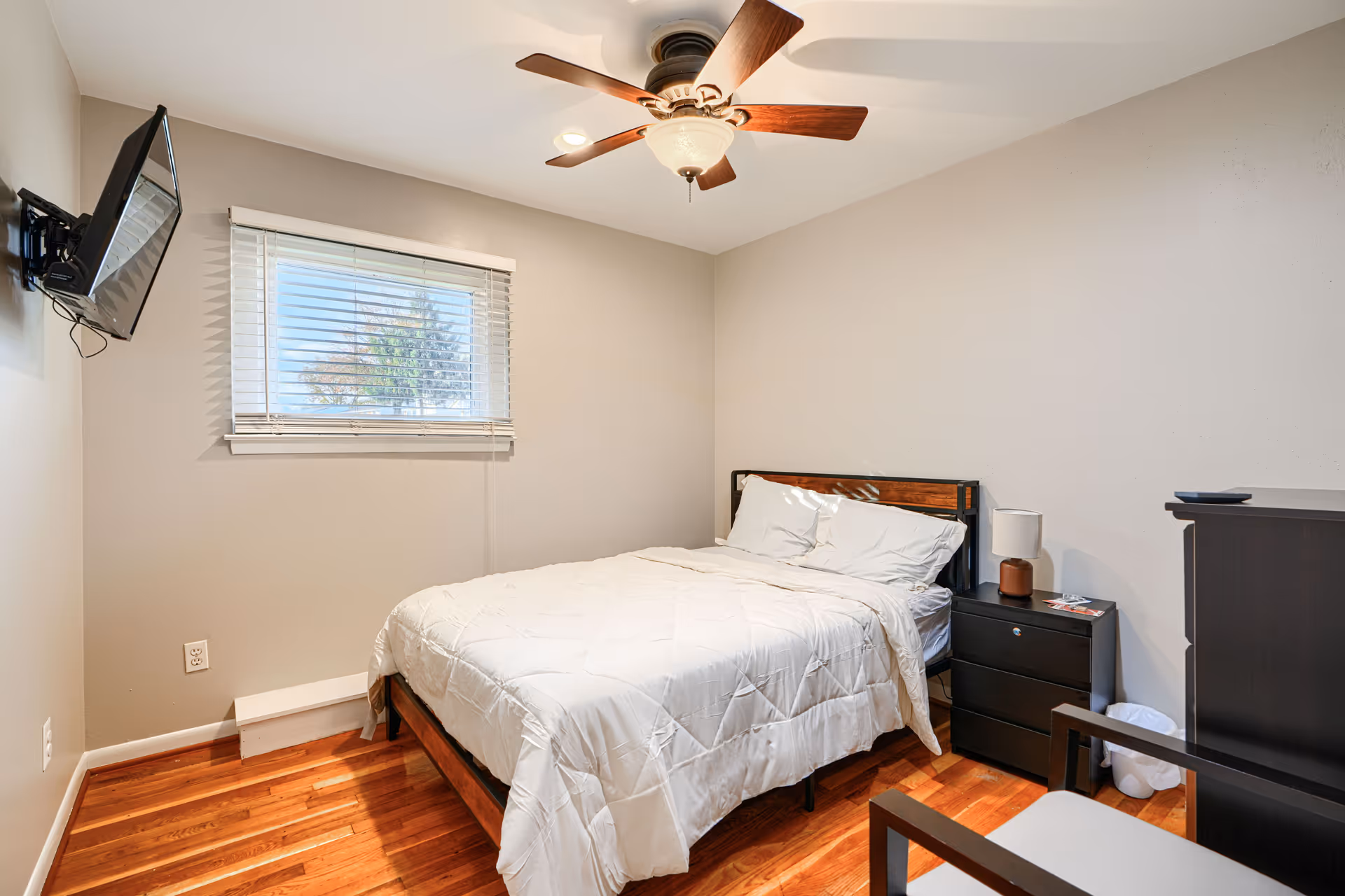 Neatly made bedroom featuring a bed, nightstands, dresser, window, and ceiling fan.