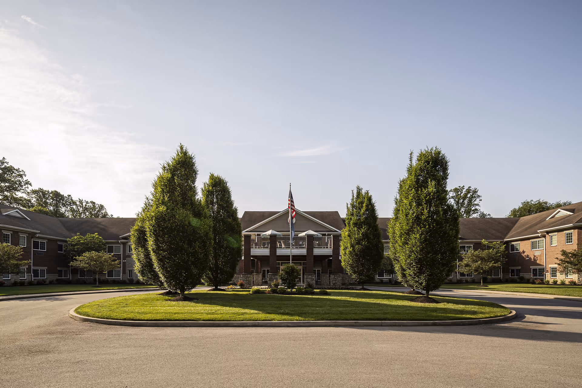 Circular driveway in front of Magnolia Springs East Louisville with a brick building and trees.