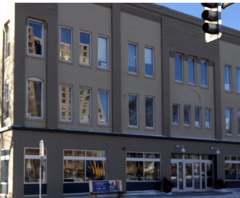 Facade of a multi-story building with large windows and storefront entrances.