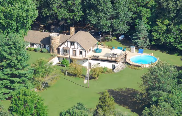 Aerial view of Cedar Springs Assisted Living exterior with pool, deck, and green lawn.