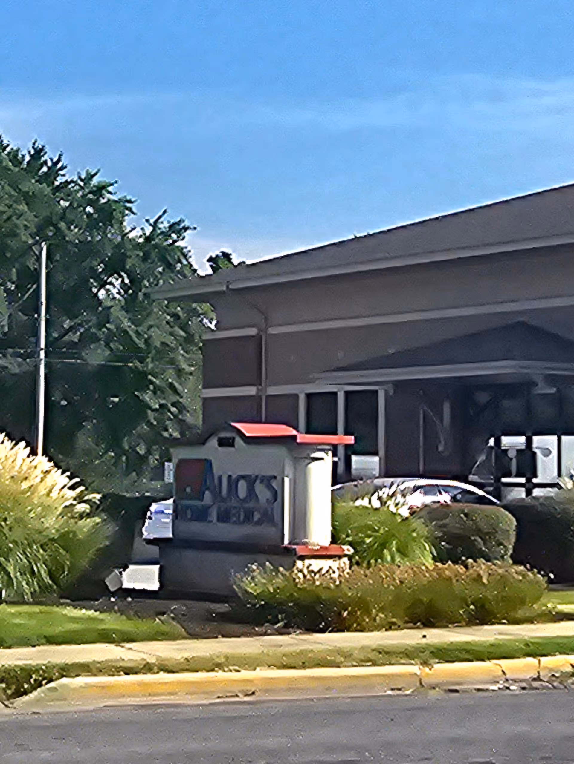 Exterior view of Alick's Home Medical facility with sign and surrounding landscaping.