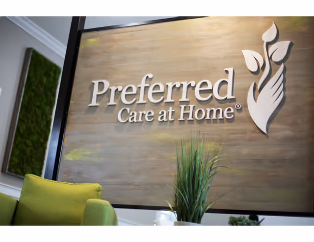 Lobby interior with a large Preferred Care at Home sign and green seating.