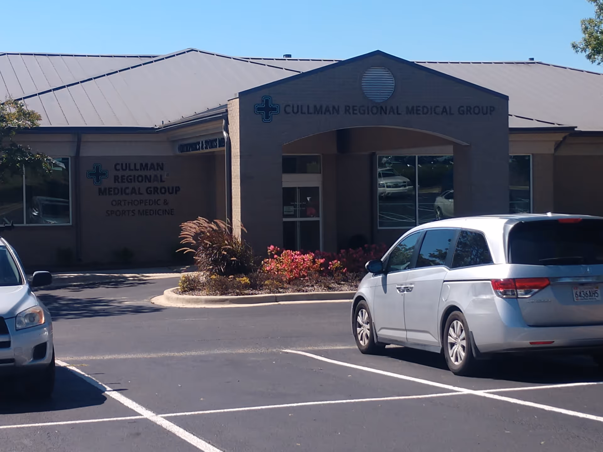 Exterior view of Cullman Regional Medical Group entrance with parked cars in foreground.