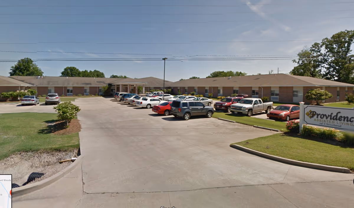 Exterior view of a single-story brick senior living facility with a parking lot.