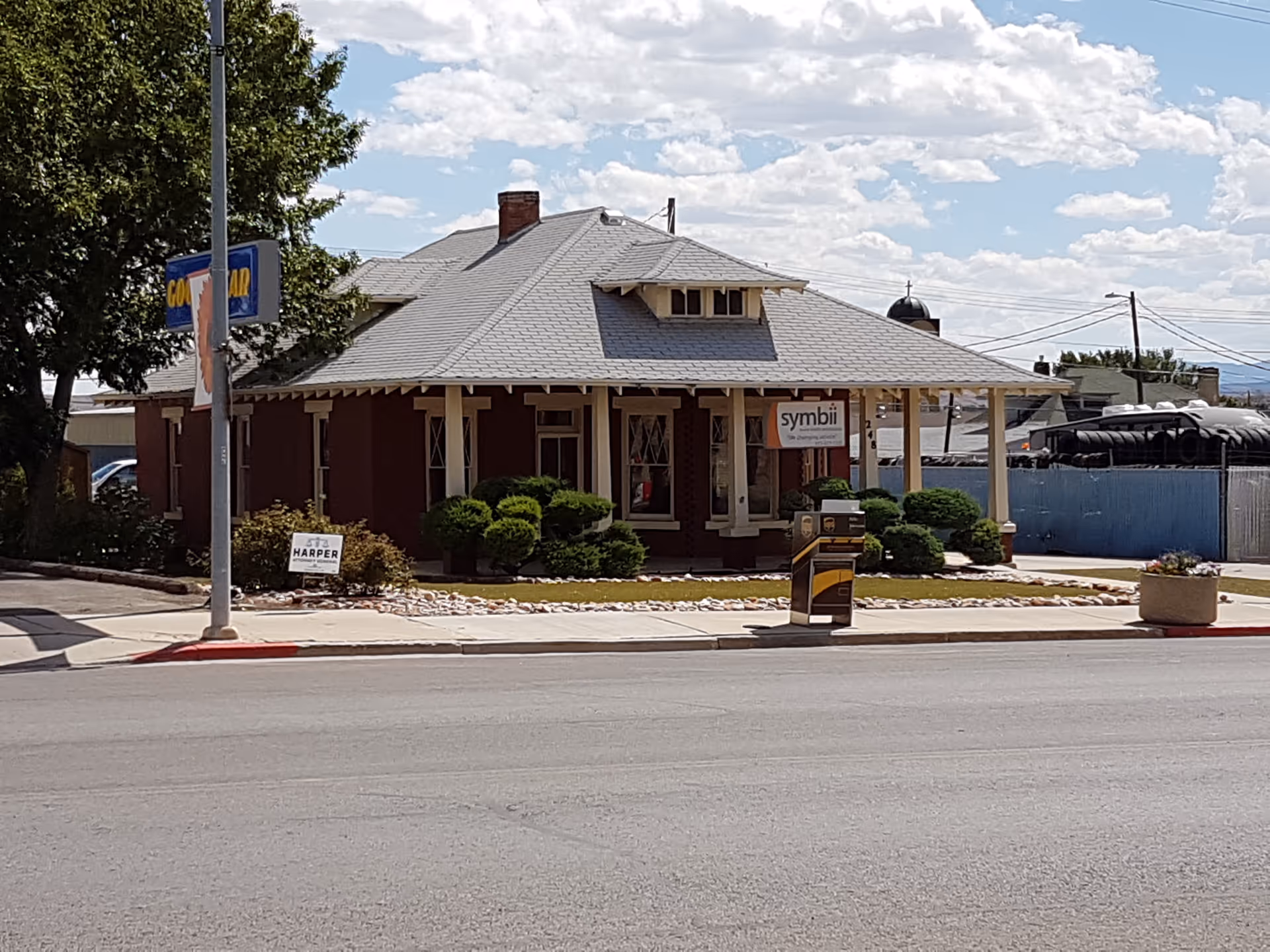 Brick building with a covered porch and Symbii sign along the street.
