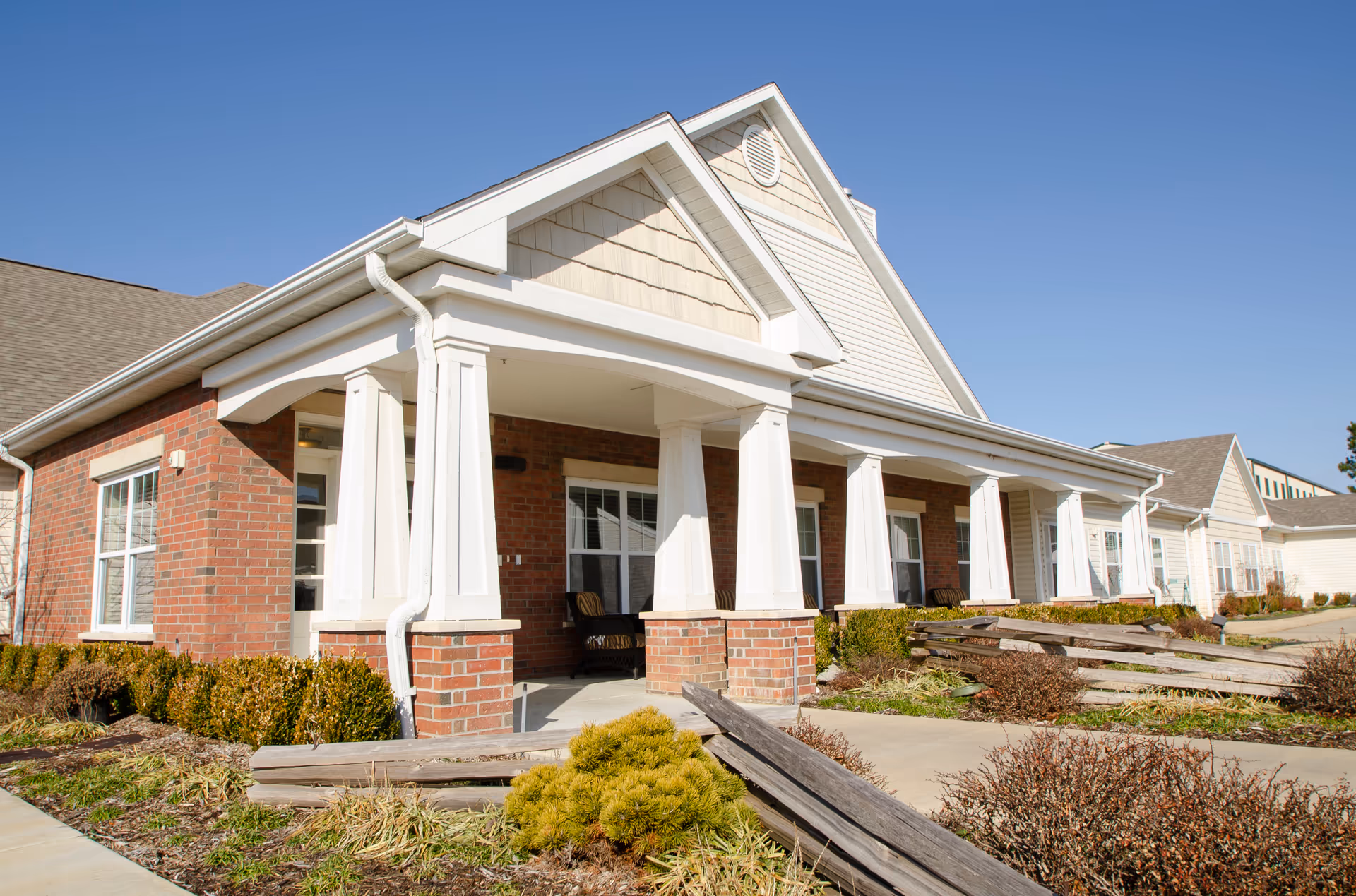 Single-story brick senior living facility with white columns and a covered front porch.