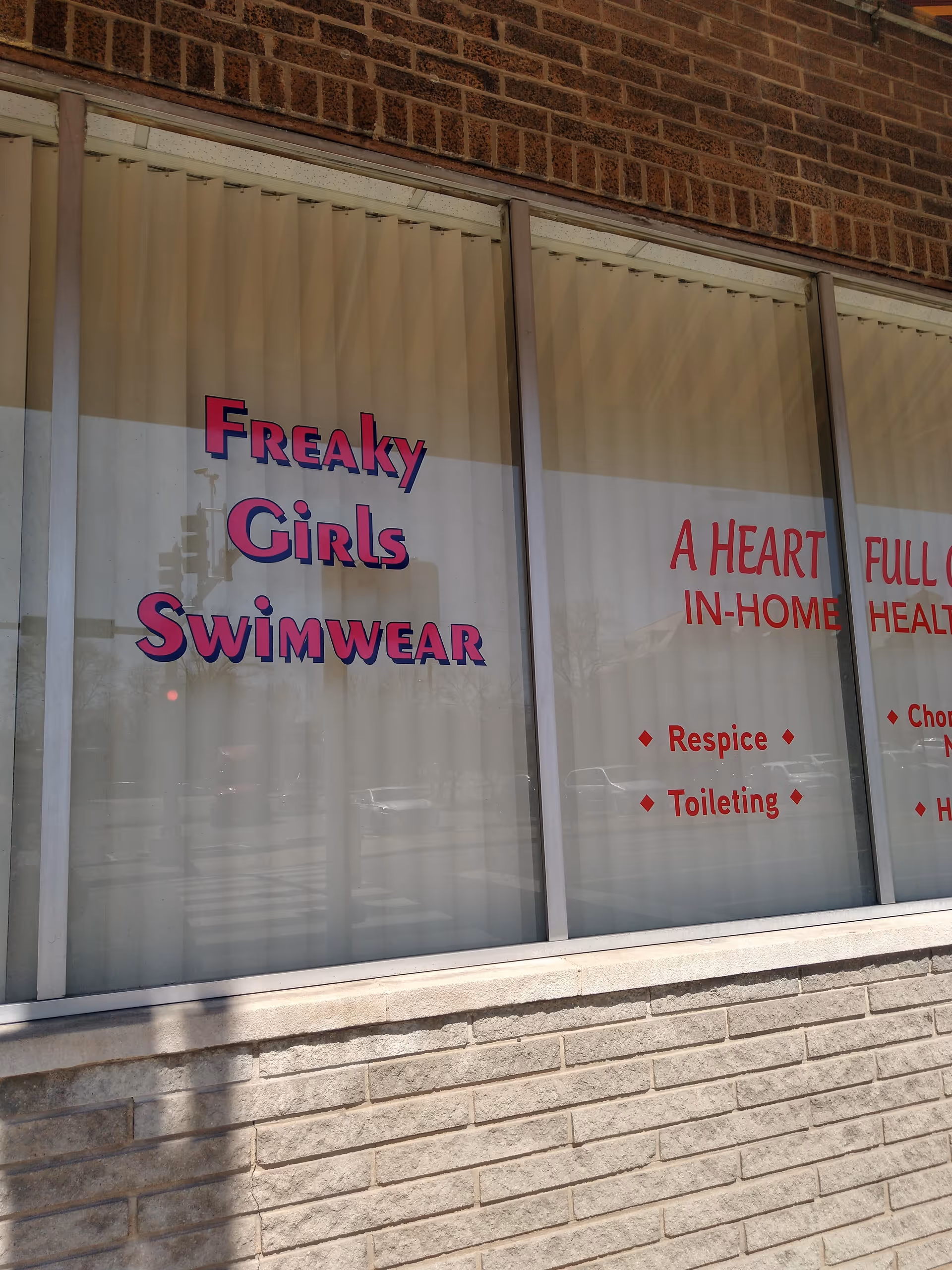 Brick building facade with window signs for Freaky Girls Swimwear and A Heart Full of Love