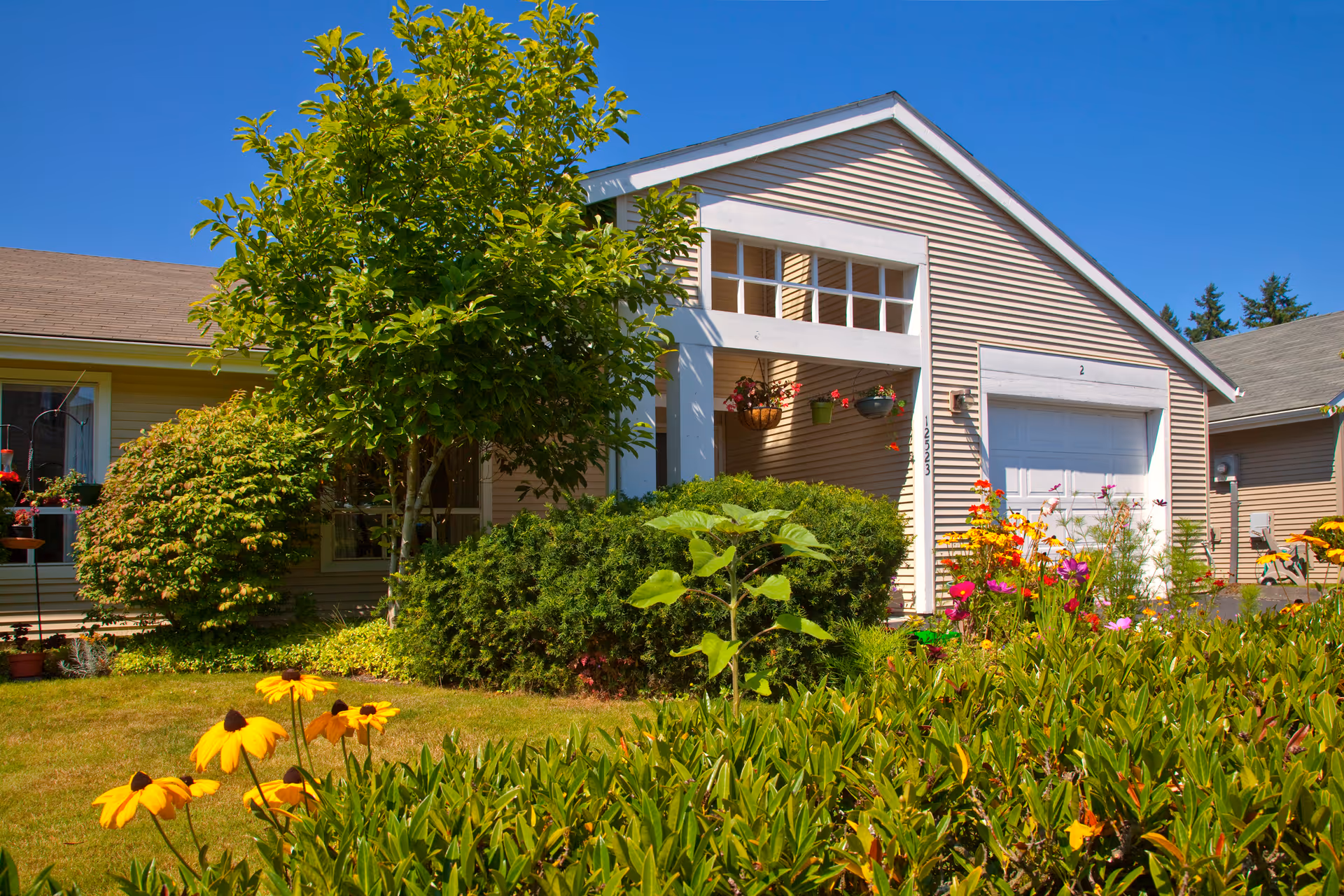 A single-story senior living home with a manicured garden and colorful flowers in front.