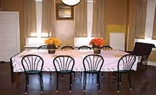 Long dining table with pink tablecloth and chairs in a bright assisted living dining room