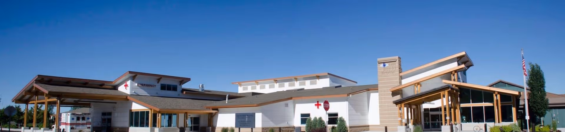 Wide view of a modern senior living facility exterior with a long entrance and canopies.