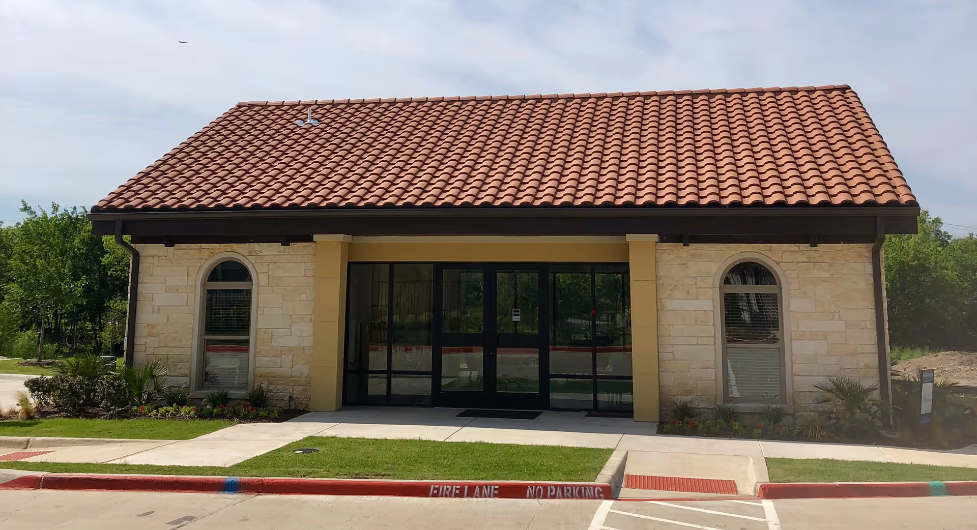 Front view of Magnolia Assisted Living building with a red tile roof and glass entrance.