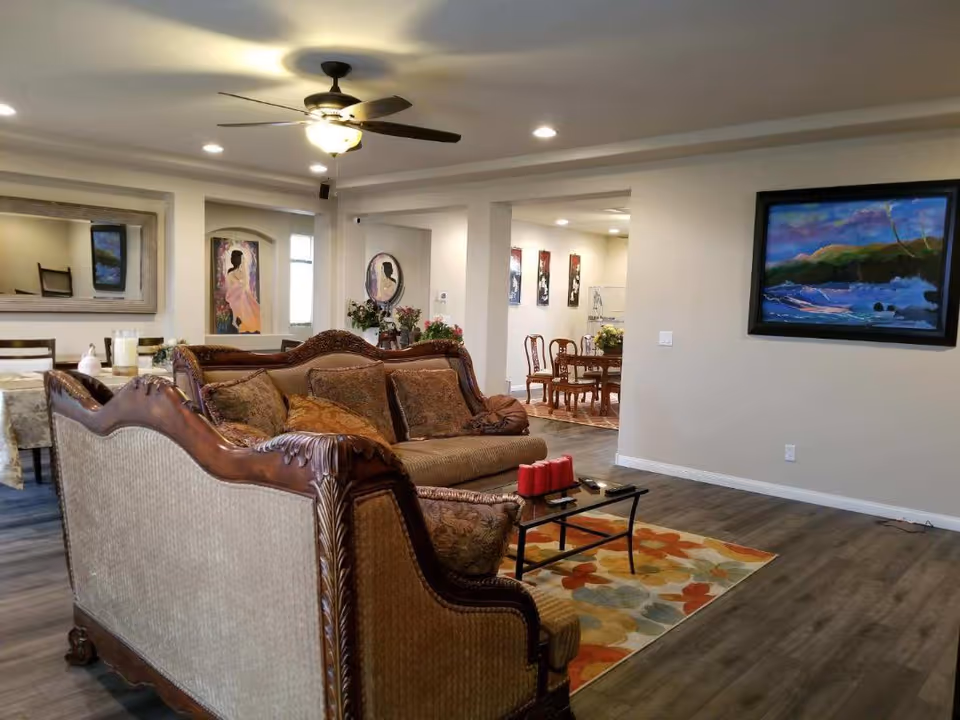 Spacious senior living common area with a sofa, artwork, and dining area.